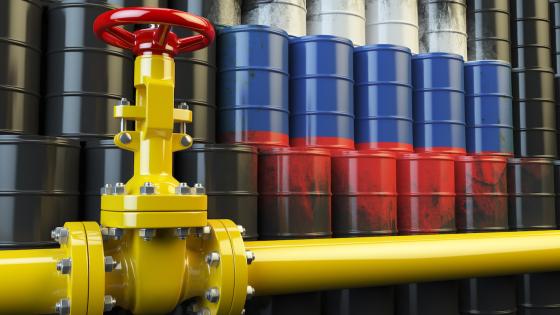Oil pipe line valve in front of the russian flag on the oil barrels