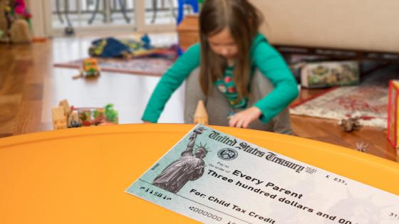 Child tax credit cheque with child playing in background