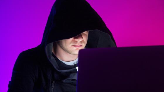 person on a laptop with his hood up