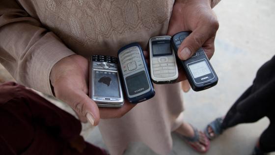Afghan man holding several mobile phones
