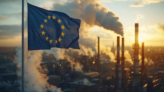 Eu flag in front of a factory chimney emitting smoke