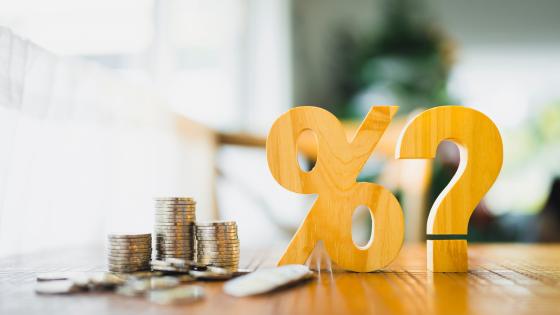 Percent symbol, question mark and pile of coins